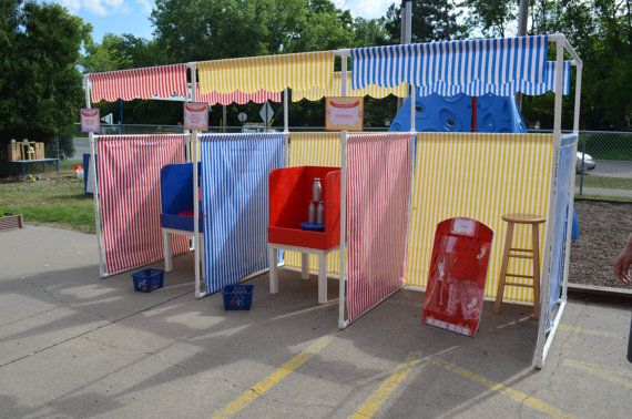 several different colored chairs are lined up on the side of the road in front of a carnival booth