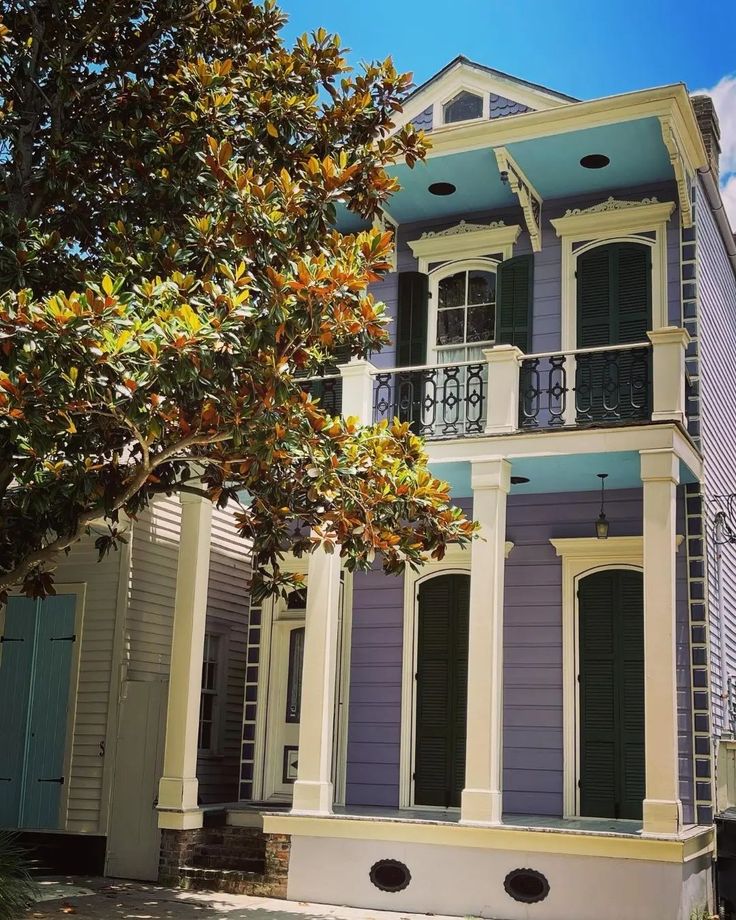 an old house painted in shades of blue and yellow with green shutters on the second story