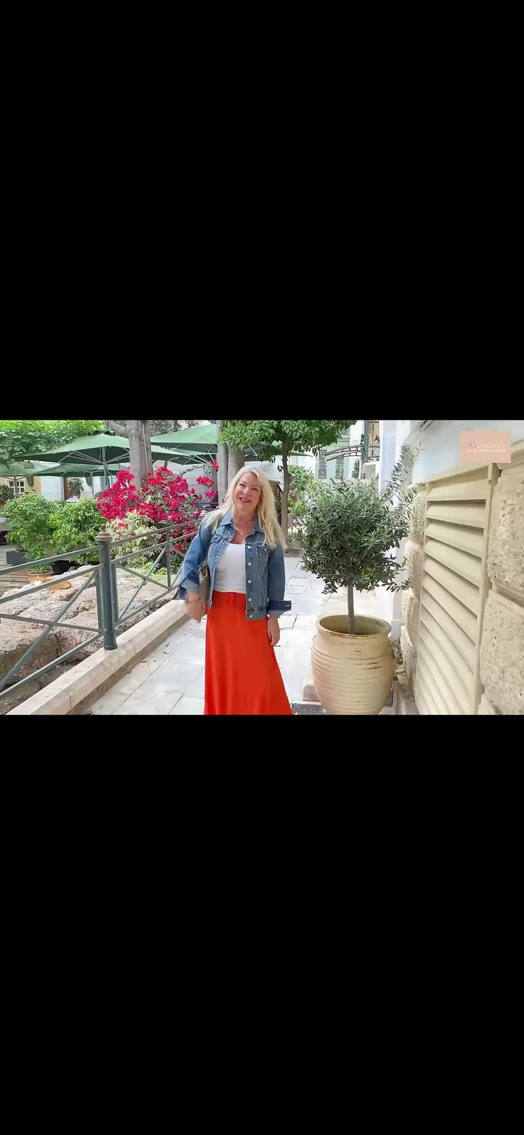 a woman standing next to a tree in front of a building