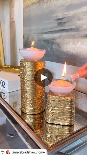 two gold candles sitting on top of a glass table