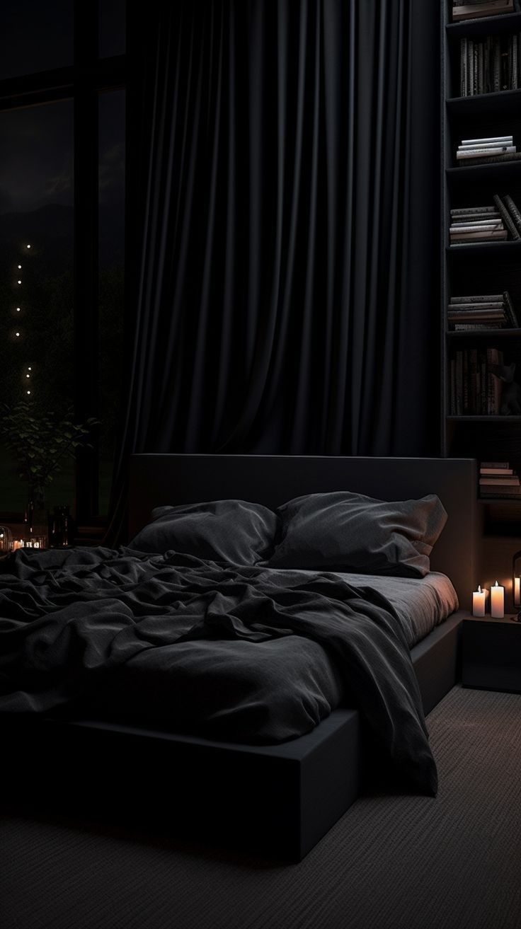 a bed with black sheets and pillows in a dark room next to a bookshelf