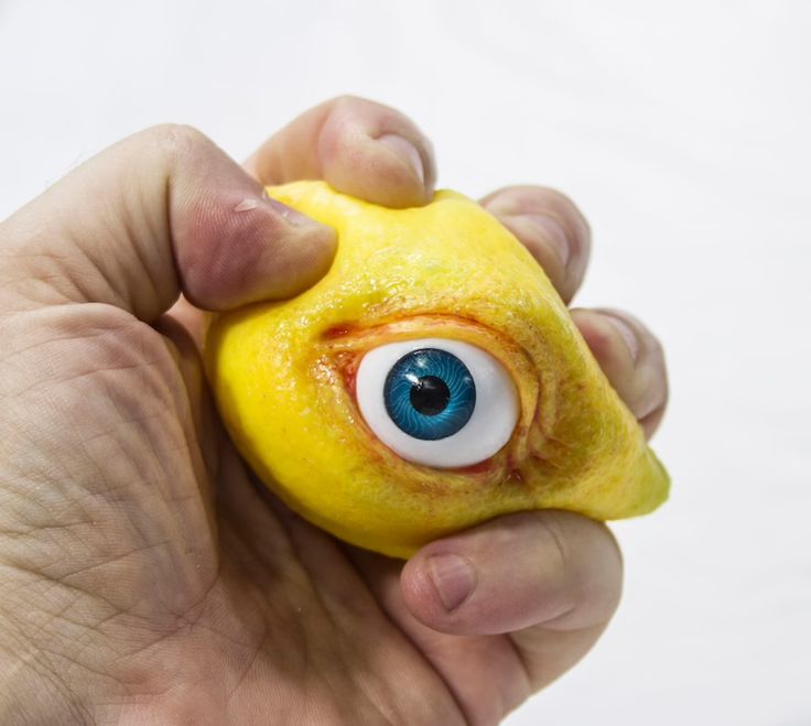 a hand holding a yellow toy with an eye on it