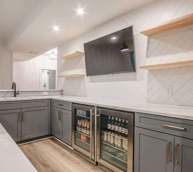 a kitchen with gray cabinets and white counter tops, television above the refrigerator in the corner