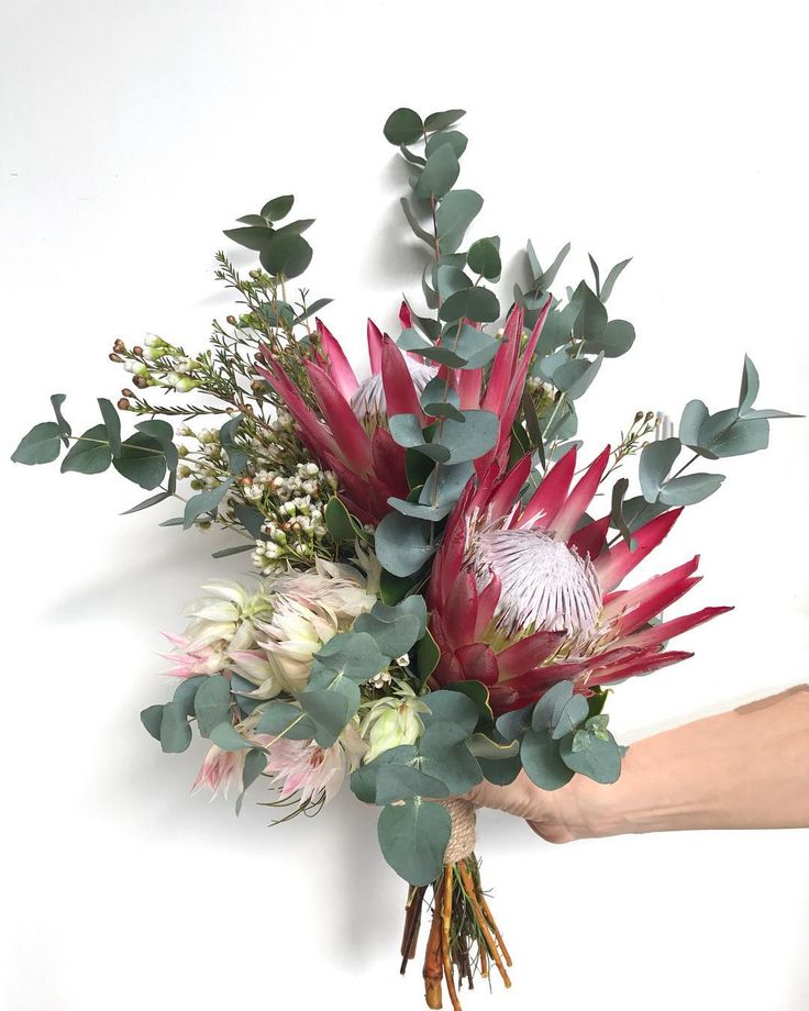 a hand holding a bouquet of flowers and greenery