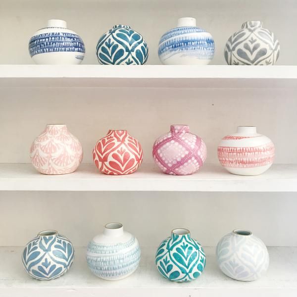 many different colored vases on shelves in a display case with white and blue designs