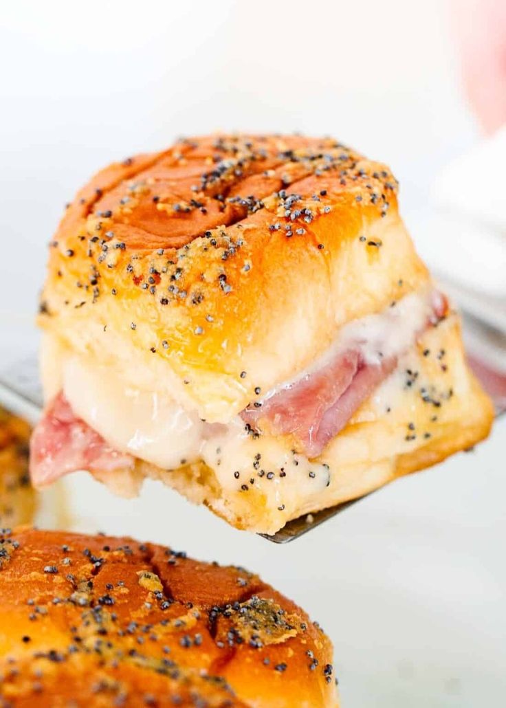 a ham and cheese sandwich being held up by a fork with the rest of the sandwich on it