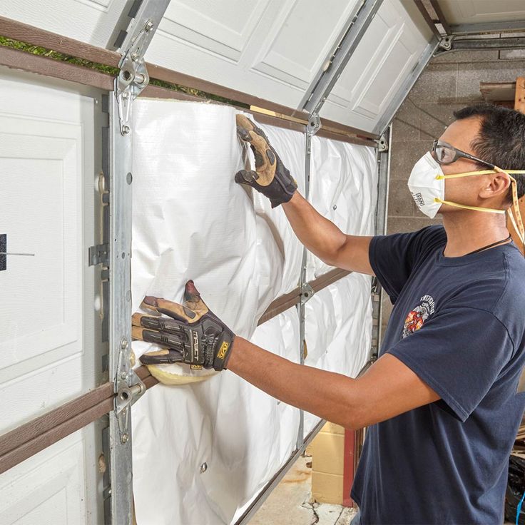 a man in a blue shirt and gloves working on a wall