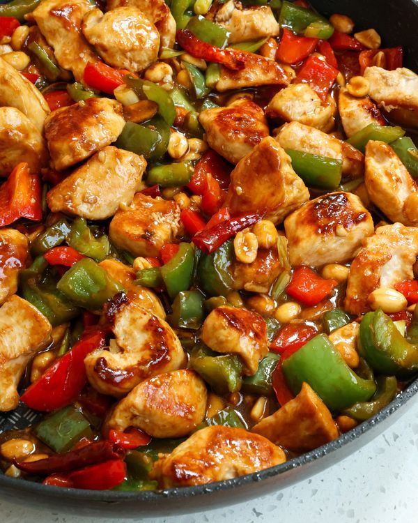 a pan filled with chicken, peppers and cashews on top of a table