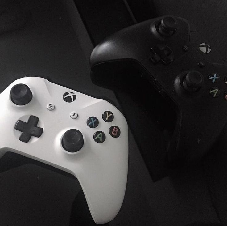 two video game controllers sitting next to each other on a black counter top in a dark room