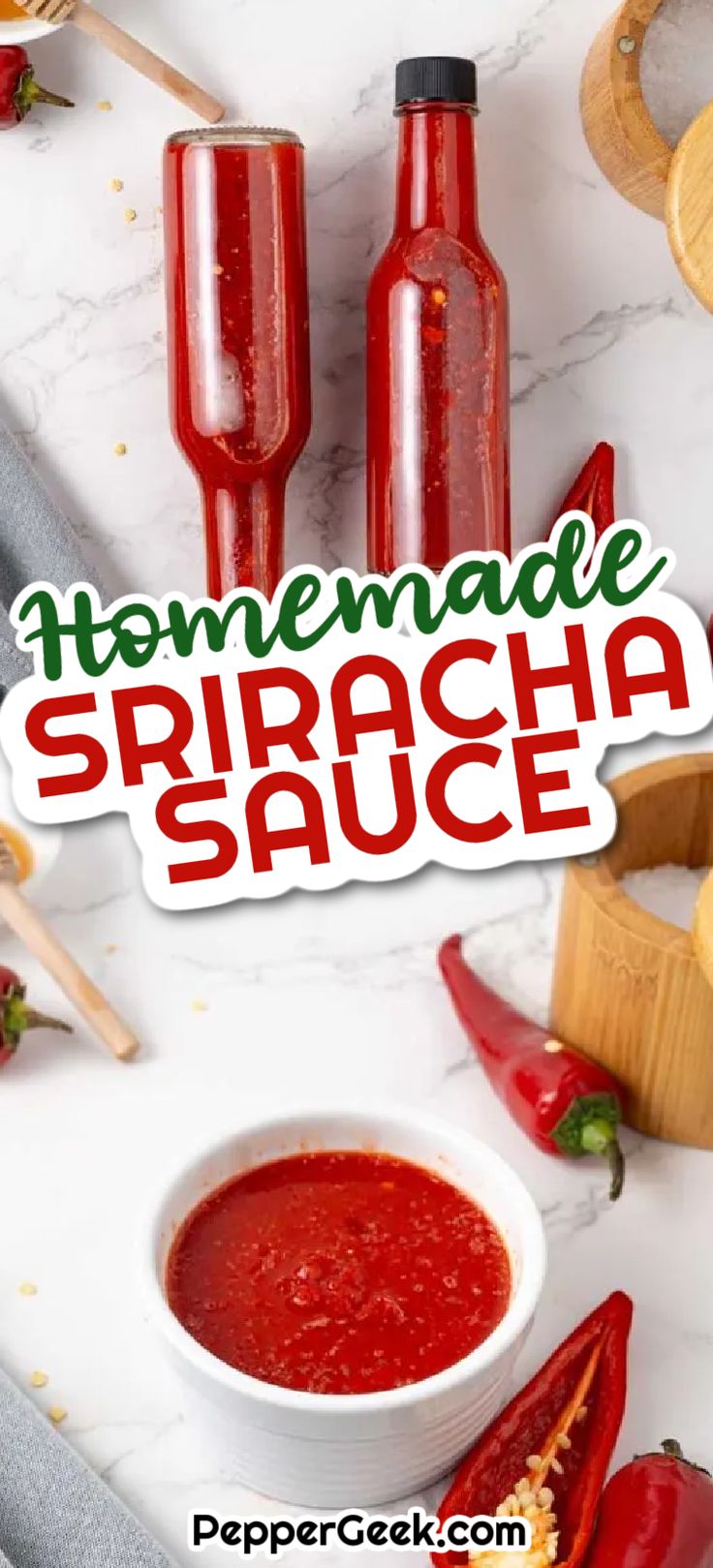 homemade sriraca sauce in two bottles on a marble counter top with peppers and garlic