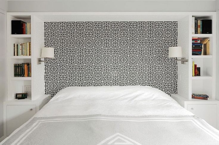 a white bed sitting under a book shelf filled with books