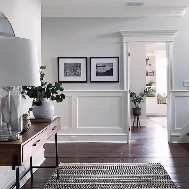 a living room filled with furniture and pictures on the wall next to a table topped with a lamp