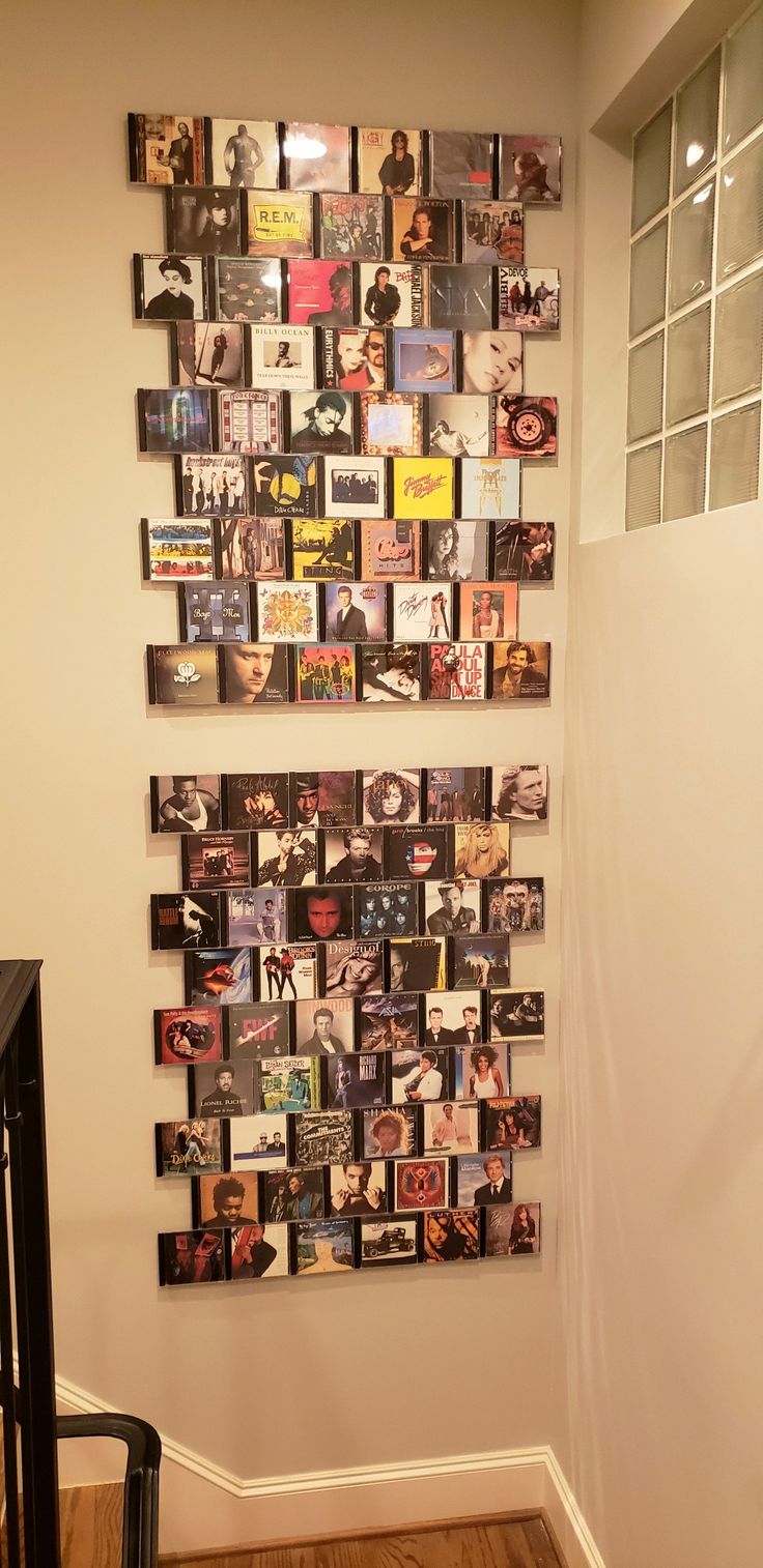 a wall with many pictures on it and a stair case in the corner behind it