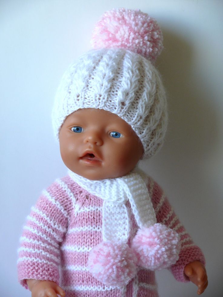 a baby doll wearing a pink and white knitted outfit with pom - pom