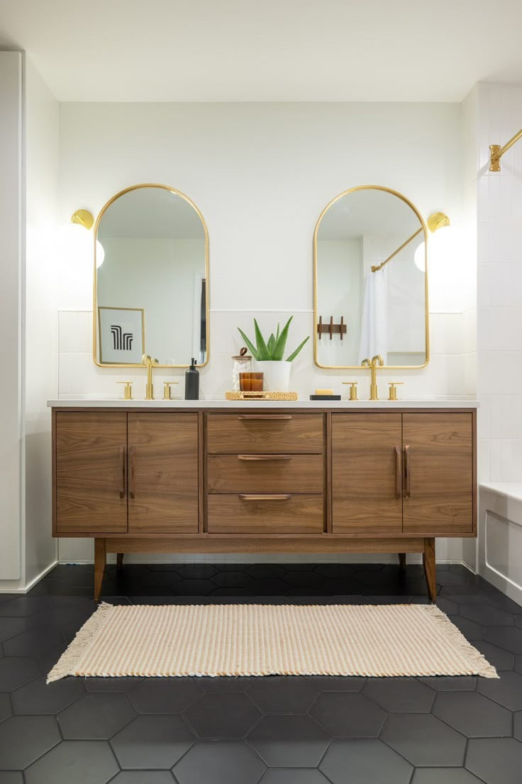 a bathroom with two mirrors and a rug on the floor in front of it,