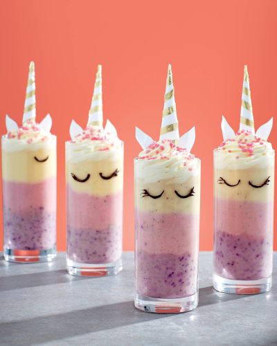 three glasses filled with unicorn themed desserts on top of a table