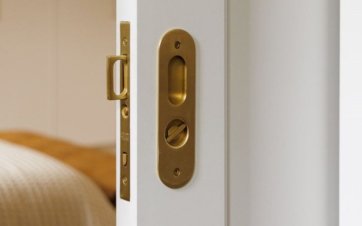 an open door with a handle on the outside of it and a bed in the background