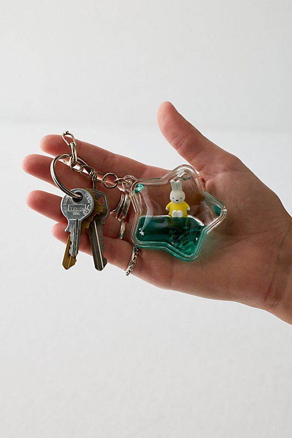 a hand holding two keys and a bottle with a lego figure in it