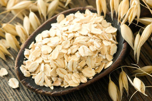 a wooden spoon filled with oats on top of a table