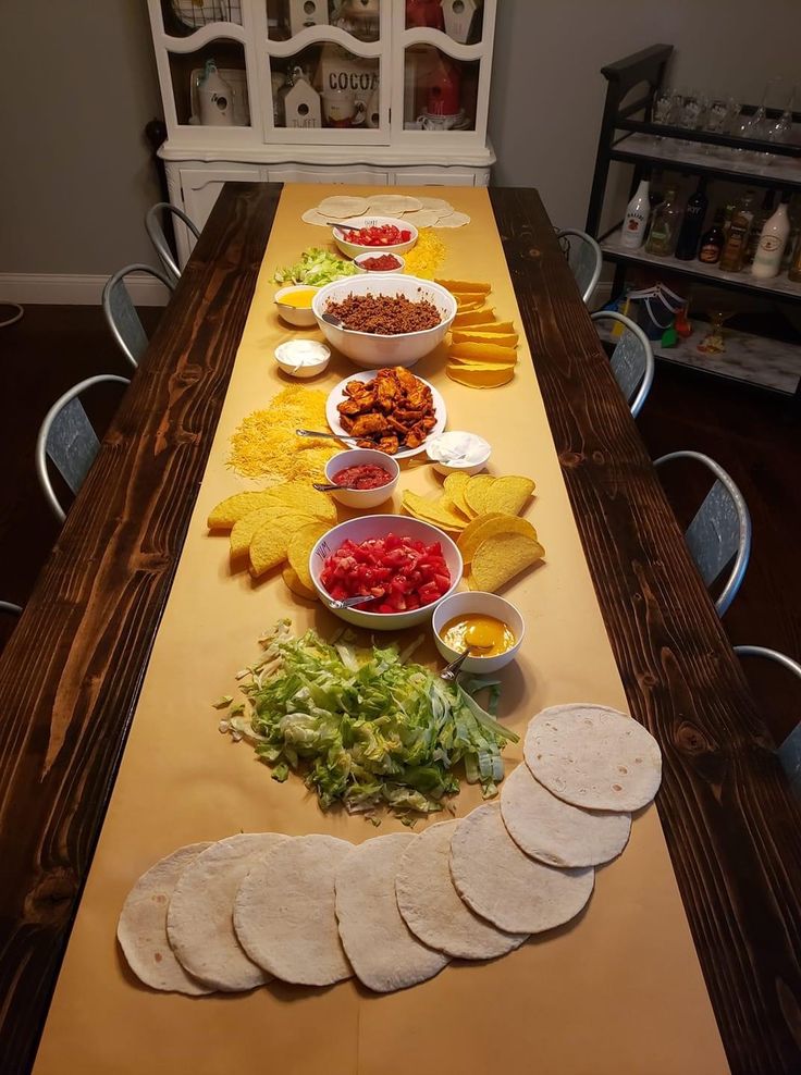 a long table with tortillas, salsa and other food items on the table