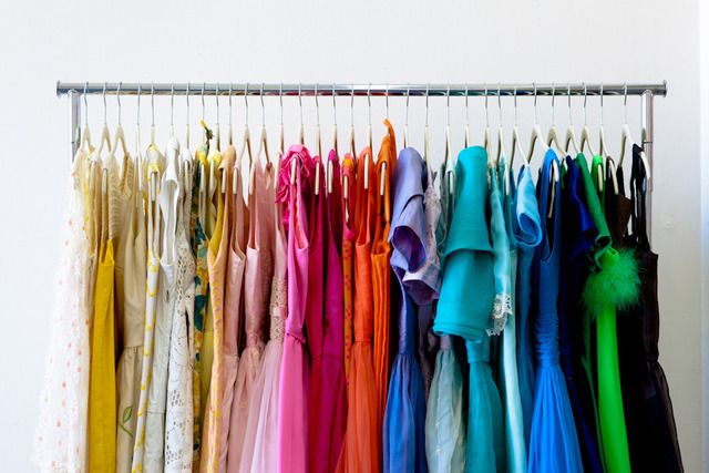 there are many different colored dresses hanging on the clothes rack in front of each other