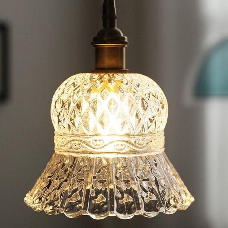 a glass light fixture hanging from a ceiling in a room with a blue lamp shade