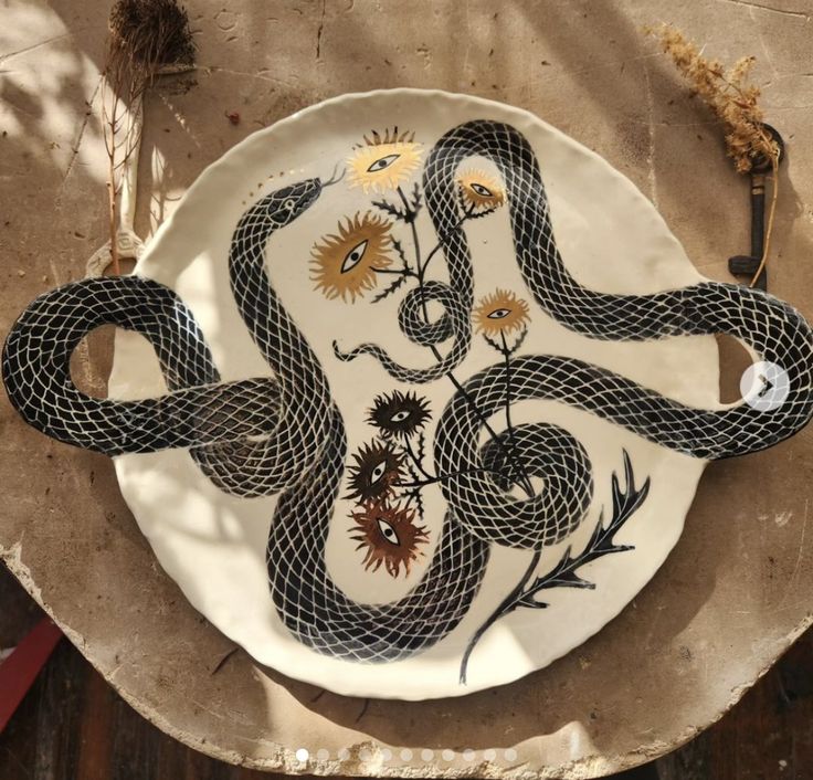 a plate with a snake and flowers painted on it