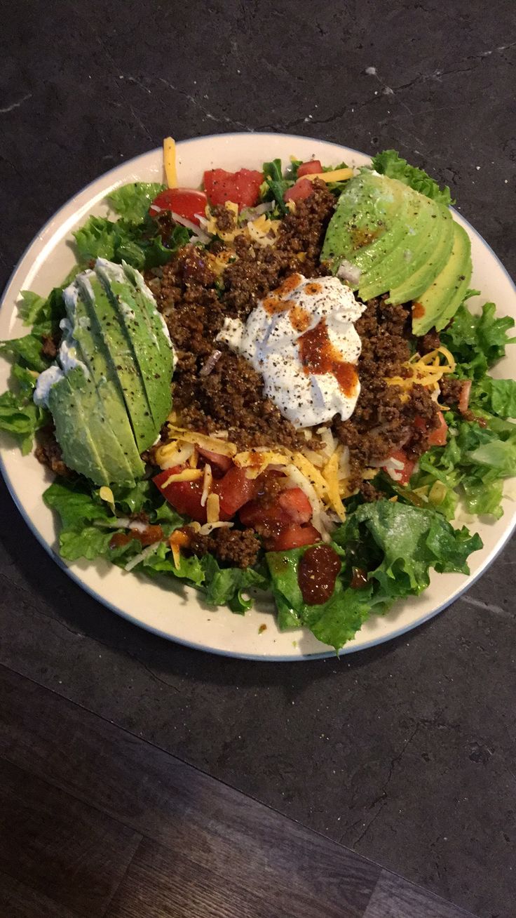 a white plate topped with lettuce, cheese and other toppings on top of it