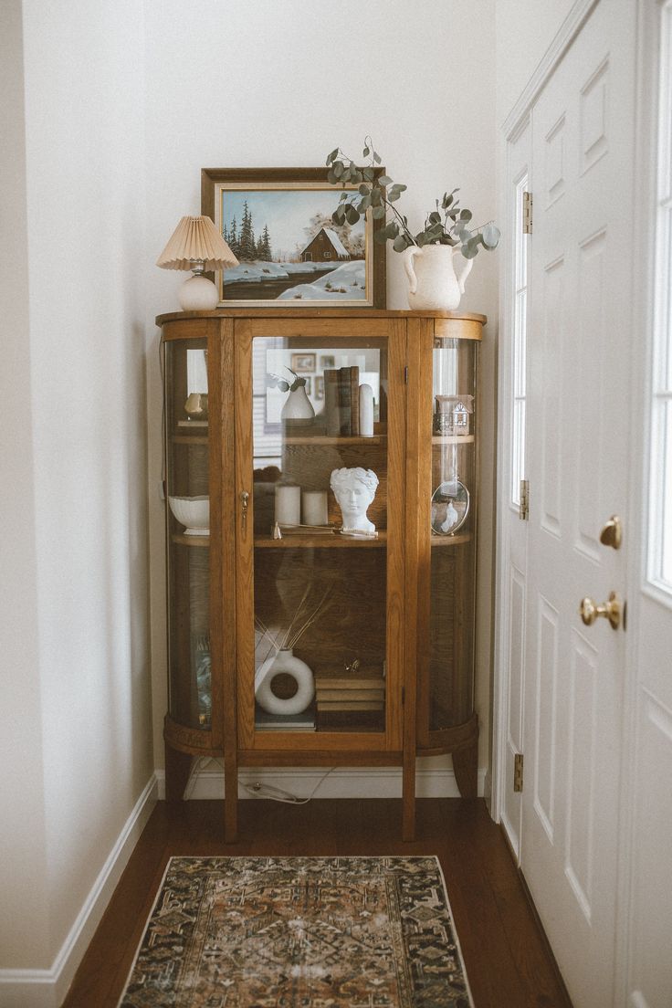 a wooden cabinet sitting in the corner of a living room next to a white door