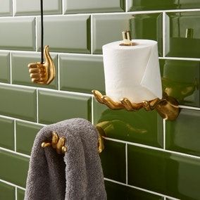 two rolls of toilet paper are hanging on the wall next to a towel rack with gold handles