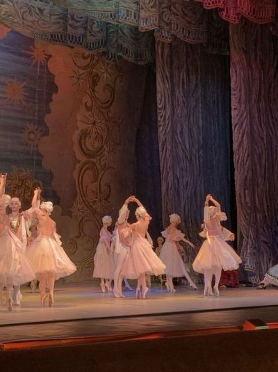 a group of ballerinas on stage in white dresses and tulle skirts with their arms raised