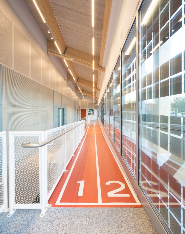 an empty hallway with red and white markings on the floor next to glass doors that lead into another building