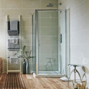 a bathroom with wooden flooring and white tile on the walls, along with a walk in shower