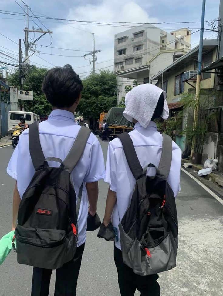 two people with backpacks walking down the street