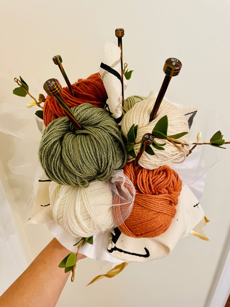 yarn and crochet needles arranged on top of each other in a bouquet with leaves