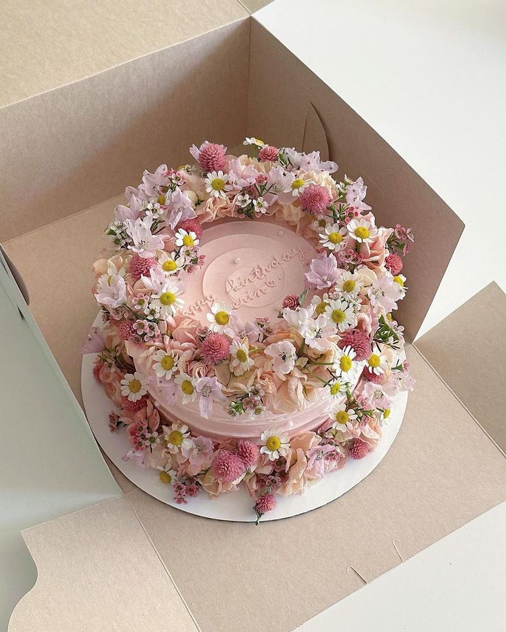 a cake in a box with flowers on it that is decorated like a flower wreath