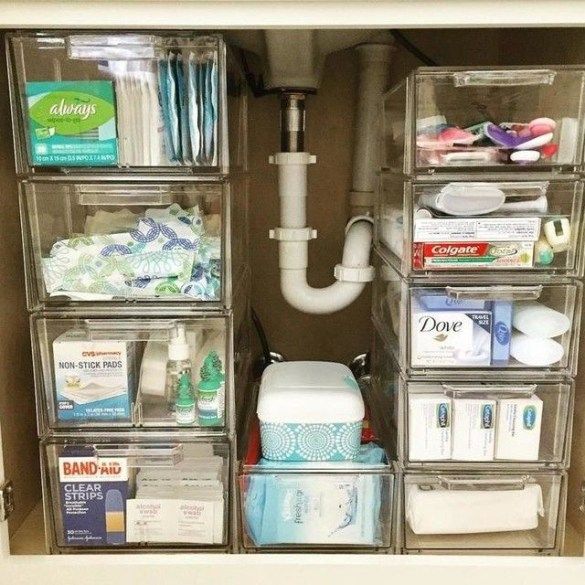 the inside of a bathroom cabinet with clear drawers and plastic bins filled with toiletries