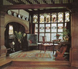 an old fashioned living room with stained glass windows and wood trimming on the walls