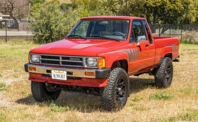 a red pick up truck parked on top of a grass covered field