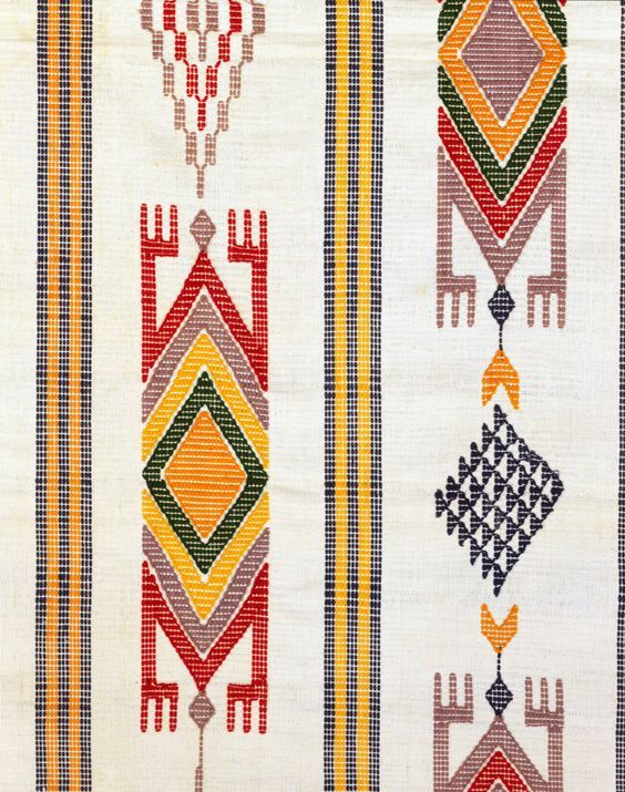 an old rug with different designs and colors on the side, including arrows in red, yellow, green, orange, and blue