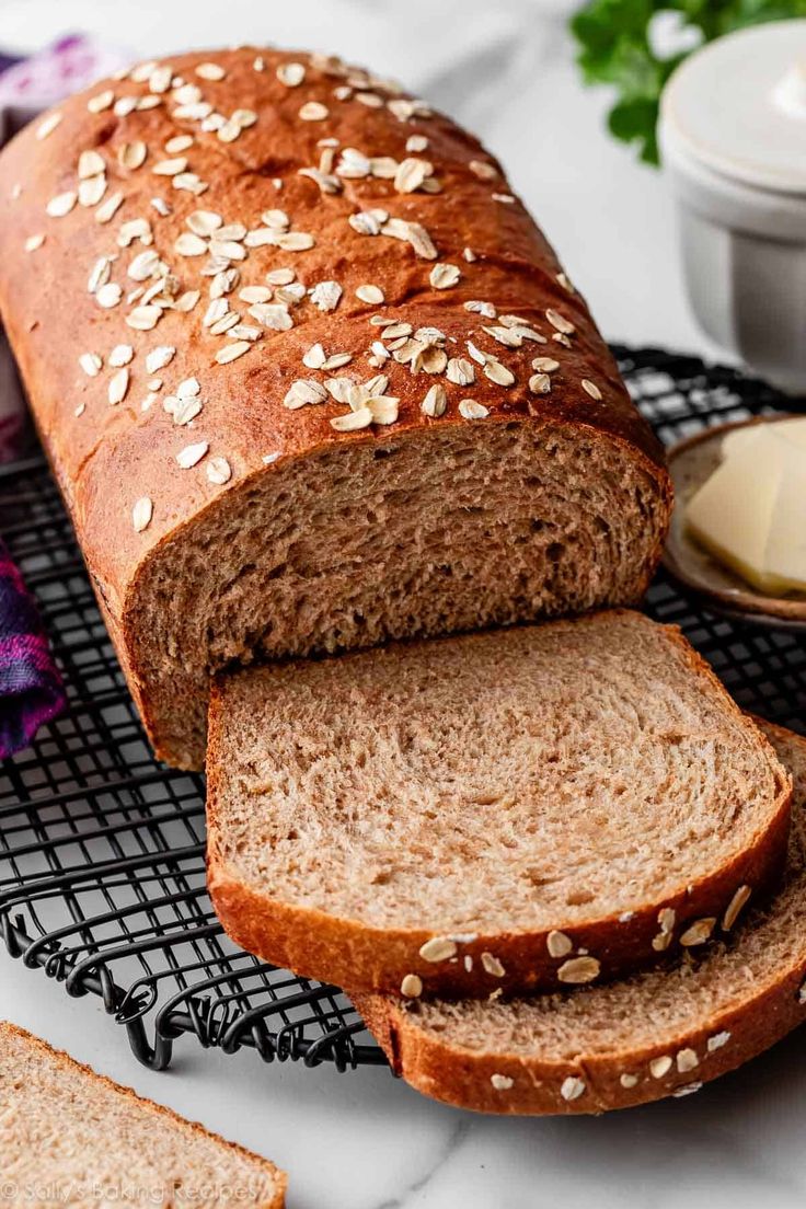 a loaf of bread sitting on top of a cooling rack next to slices of bread