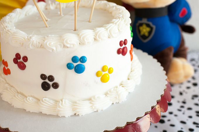 a birthday cake decorated with paw prints on it and a teddy bear next to it