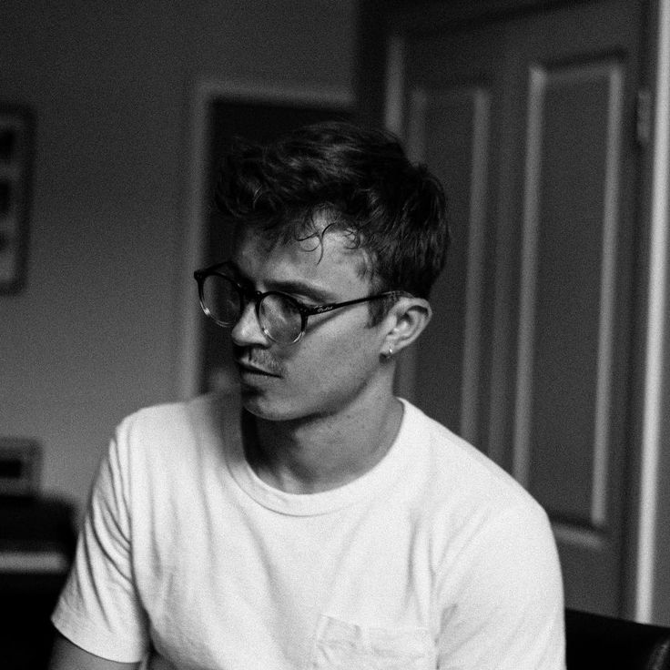 black and white photograph of a young man wearing glasses looking at something in the distance