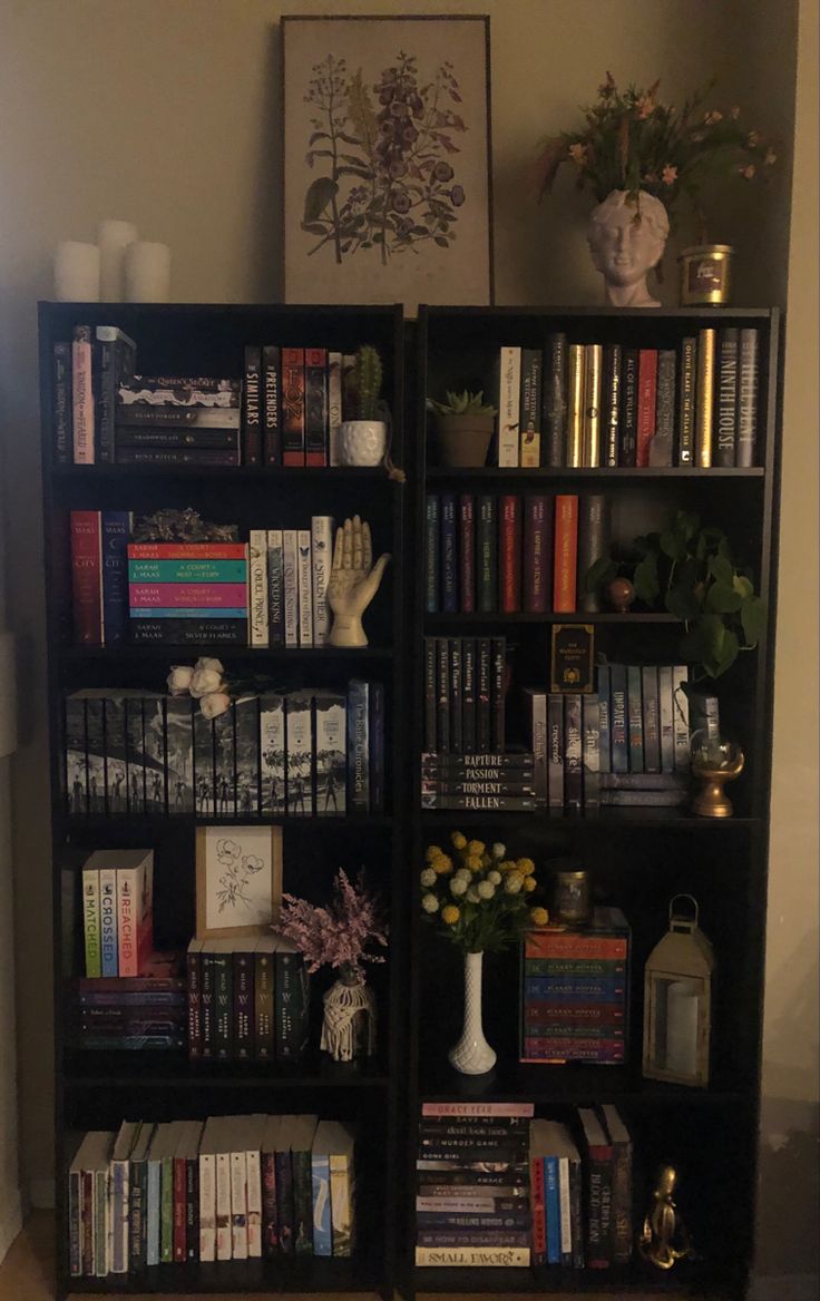 a bookshelf filled with lots of books next to a vase full of flowers