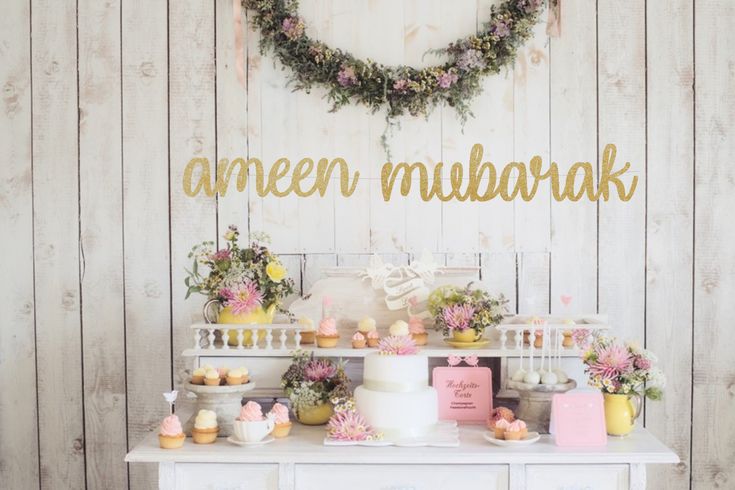 a table topped with cakes and cupcakes next to a white dresser covered in flowers