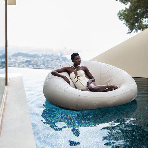 a man sitting on an inflatable chair next to a swimming pool