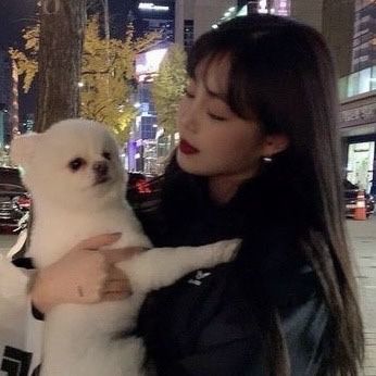 a woman holding a small white dog in her arms