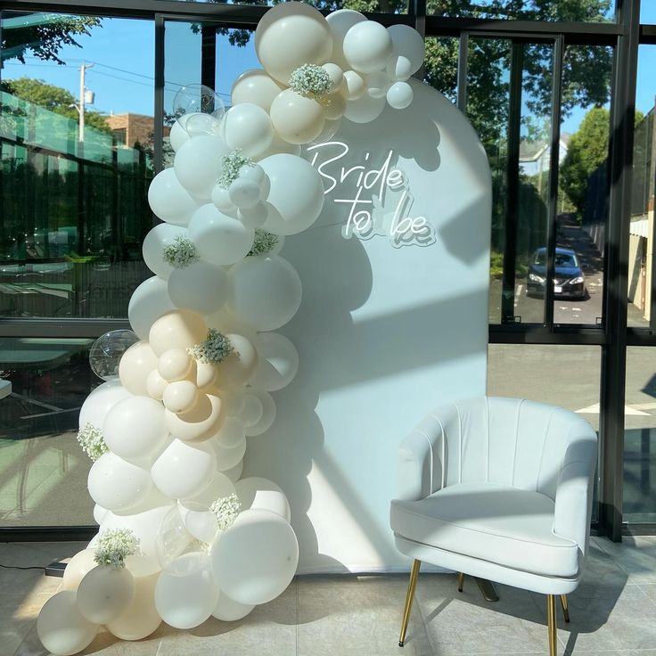 a white chair sitting in front of a large balloon arch