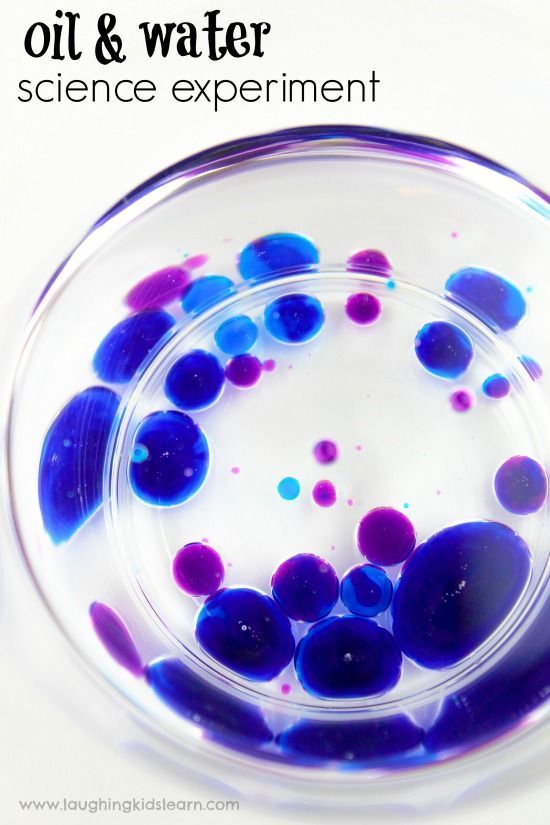 an oil and water experiment in a glass bowl with blue and purple bubbles on it