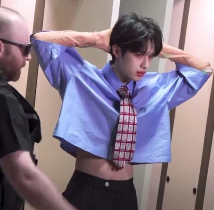 a man wearing a tie standing in front of a mirror with his hands on his head